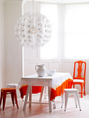 Tie-dyed tablecloth with orange chair in bright room