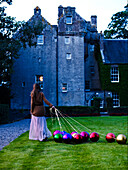 Woman pulls metallic baubles across lawn Scotland UK