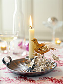 Gold bird ornament with silver flowers and lit candle