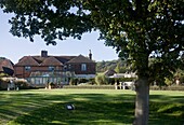 Conservatory extension and lawned exterior of farmhouse in Grafty Green, Kent, England, UK