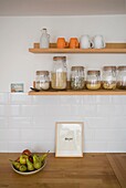 "Vorratsgläser und eine Schale mit Birnen mit dem Schriftzug Enjoy"" auf einer hölzernen Küchenarbeitsfläche in einem Haus in St Leonards, East Sussex, England, UK"""