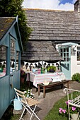 Picknicktisch und -bank mit Wimpel und Schuppen im Garten eines Cottages, Corfe Castle, Dorset, England, UK