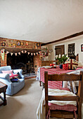 Light blue armchair next to brick fireplace with bunting in dining room of Egerton cottage, Kent, England, UK