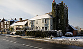 Painted home exterior with ivy clad tower and snowfall in Tenterden, Kent, England, UK