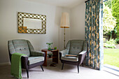 Vintage armchairs and mirror at curtained doorway in modern home Bath Somerset, England, UK