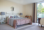 Rosa und graues Mobiliar auf einem Bett mit Metallrahmen in einem modernen Haus in Bath Somerset, England UK