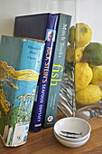 Lemons and limes in glass vase with books on seafood cooking in Dartmouth home, Devon, UK