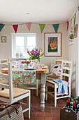 Wine crate with painted chairs at kitchen table with bunting in High Halden farmhouse Kent England UK