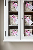 Bathroom storage baskets in glass fronted cabinet Kilndown home Cranbrook Kent England UK