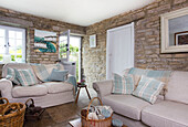 Checked cushions on sofas in exposed stone living room of Worth Matravers cottage Dorset England UK