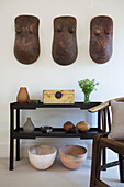 Tribal torsos above console table with ornaments in Wandsworth home London England UK