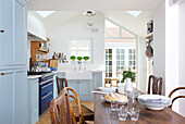 Tableware and bread on wooden table in light blue Emsworth kitchen Hampshire England UK