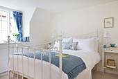 Weißes schmiedeeisernes Doppelbett mit blauer Decke in Dorset Cottage Corfe Castle England UK