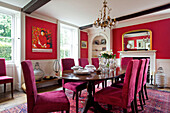 Pink velvet upholstered dining chairs in red dining room of Bishops Sutton home Alresford Hampshire England UK