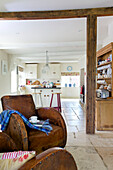 Pair of matching brown leather armchairs with view to open plan kitchen in Bishops Sutton home Alresford Hampshire England UK