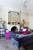 Grey upholstered sofa with pink armchairs in living room of Hackney home London England UK