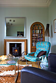 Türkisfarbener Sessel und Holzofen im Wohnzimmer eines Hauses in Faversham, Kent, England, UK