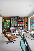 Stühle und Bücherregal in einem offenen Strandhaus in Rye, East Sussex, Großbritannien