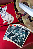 Vintage French magazines with bulldog cushion on chair in Tenterden home Kent UK