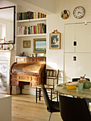 Antique writing desk and bookshelves in open plan dining room of London home England UK