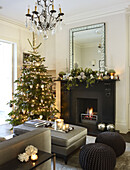 Christmas tree at fireplace with silver ottoman in London home England UK
