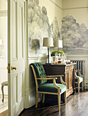Matching lamps on wooden sideboard with wall frieze in dining room of East Sussex country house England UK