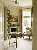 Marble topped side table and bookcase with armchair in East Sussex country house England UK