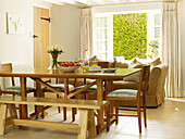 Wooden dining table and chairs with sofa and open patio doors in Nottinghamshire home England UK