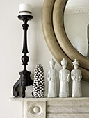 Oriental statues and candlestick with circular mirror on mantlepiece in North London townhouse England UK