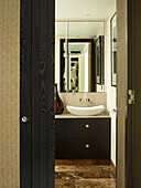 View through doorway to bathroom with mirror above sink in London townhouse, UK