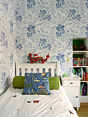 Drache am Kopfteil eines Einzelbetts mit Palmentapete im Zimmer eines Jungen, Londoner Stadthaus, UK