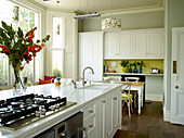 Flower arrangement on kitchen island with fitted sink and hob in London townhouse apartment, UK