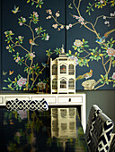 Oriental panel with birdcage reflected on polished dining table, London townhouse apartment, UK