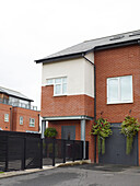 Fence and driveway with hanging baskets on brick exterior of Manchester new build, England, UK