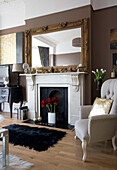 Vergoldeter Spiegel am Kamin mit Sessel im Wohnzimmer eines Hauses in Hove, East Sussex, Großbritannien