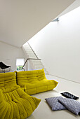 Gelbe Sitzgelegenheiten in weißer, offener, moderner Londoner Wohnung, England, UK