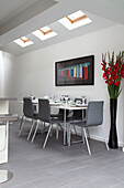 Large flower arrangement and dining table under skylights in kitchen extension of contemporary London home, England, UK