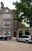 Cars parked in gravel driveway at stone exterior of London house, England, UK