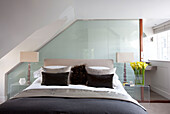 Doppelbett mit passenden Lampen und braunen Kissen in einem modernen Londoner Stadthaus, Großbritannien