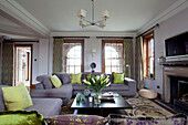 Lindgrüne Kissen auf fliederfarbenen Sofas in einem Wohnzimmer in Suffolk, UK