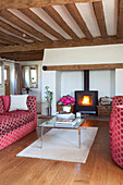 Rot gemustertes Sofa mit gläsernem Couchtisch in einem Haus mit Holzbalken in Kent, Großbritannien