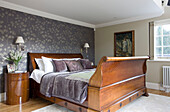 Nature inspired wallpaper and polished wooden antique bed in Surrey home UK