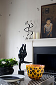 Homeware ornaments and statue with painting above fireplace in dining room in contemporary London townhouse, England, UK