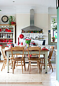 Holztisch und -stühle in einer Küche mit Kommode und Dunstabzugshaube aus Edelstahl in einem Stadthaus in London, England, Vereinigtes Königreich