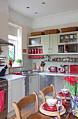 Stainless steel fitted units in kitchen with cut tulips on table in London townhouse, England, UK