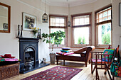 Brown leather chaise longue in bay window of living room with original fireplace in London townhouse, England, UK