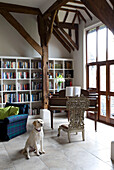 Hund sitzt im Fachwerk-Klavierzimmer mit Bücherregal Sussex UK