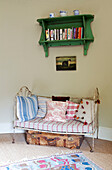 Zweisitzige Schlafcouch unter einem wandmontierten Bücherregal in einem Bauernhaus in Kent, England UK