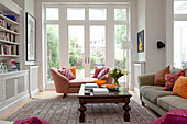 Carved wooden coffee table with double arm chaise and book shelves in contemporary London family home, UK