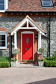 Rote Haustür eines Cottage aus Stein in Kent mit Abflussrohren in Kent, England, Vereinigtes Königreich